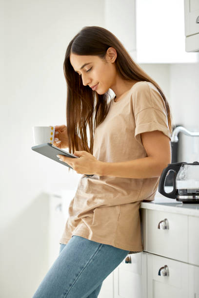 istock Young woman holding digital tablet and coffee 1127284761