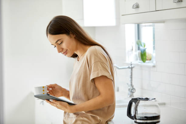 istock Young woman holding digital tablet and coffee cup 1127284762