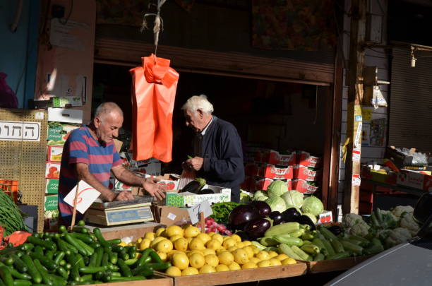 Giza, Egypt - January 23, 2025: Day at the local groceries market on the streets of Giza, famous for historic landmarks - Giza Pyramids. Giza Pyramids visible behind the market stalls where local merchants sell fruits and vegetables