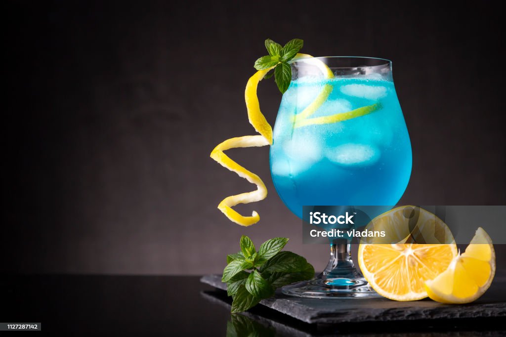 Blue lagoon cocktail Blue lagoon cocktail with blue curacao liqueur, vodka, lemon juice and soda, decorated with lemon slice and mint leaves Alcohol - Drink Stock Photo