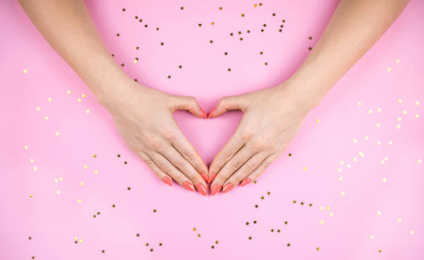 istock Woman's hand with Coral manicure making heart. 1127291012