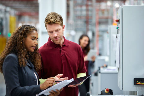 colleagues discussing over documents in car plant - plant stand imagens e fotografias de stock