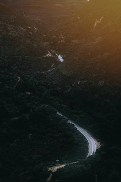 istock drone s curve road view on a mountain forest with sunflare on the top 1127293320