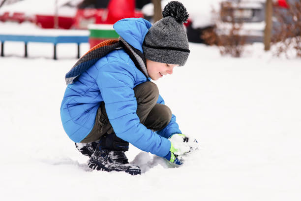 istock funny boy playing snowballs in the winter 1127295943