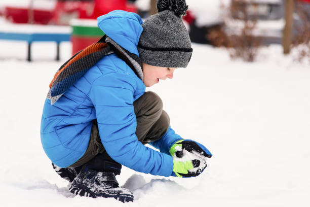 istock funny boy playing snowballs in the winter 1127295951