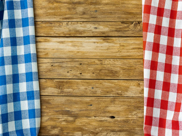 istock Old teak wood paneled wall with a high quality cotton red and blue gingham checked pattern tablecloth hanging down each side on the the paneling. 1127296311