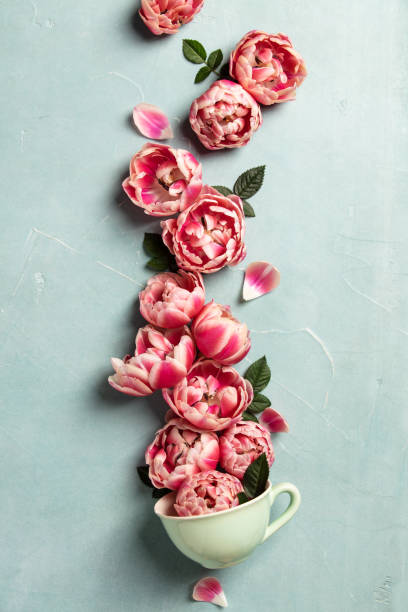 istock Creative layout made of coffee or tea cup with pink flowers on blue background 1127298956