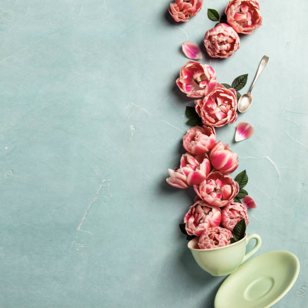Creative layout made of coffee or tea cup with pink flowers on blue background