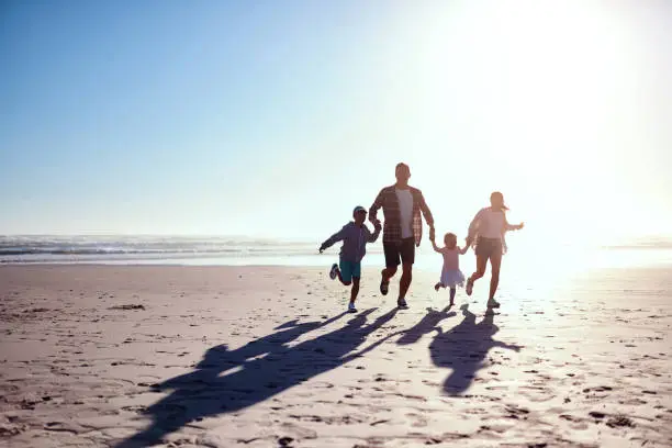 Shot of a happy young family of four running together on the beach