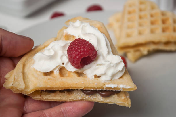 waffle in shaped heart with chocolate, chantilly cream and raspberry in hand