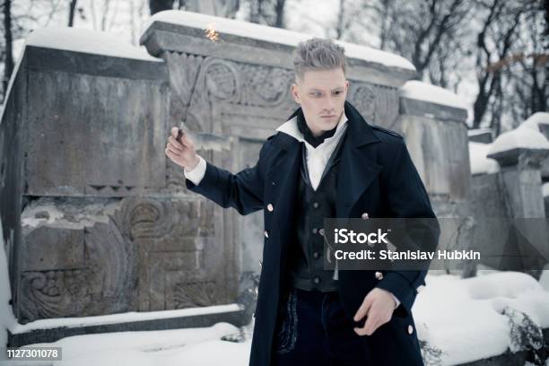 Young Man In Image Of Black Magician Makes A Spell Using Magic Wand Stock Photo - Download Image Now