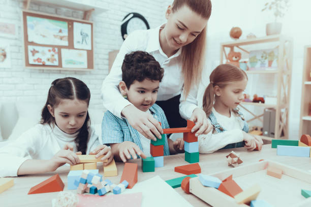 istock Kindergarten teacher helps Children fold designer 1127301132