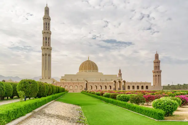 Main view of the Sultan Qaboos Grand Mosque and colorful gardens in Muscat, Oman. Amazing Islamic architecture. The Muslim place is a popular tourist attraction of the Middle East.