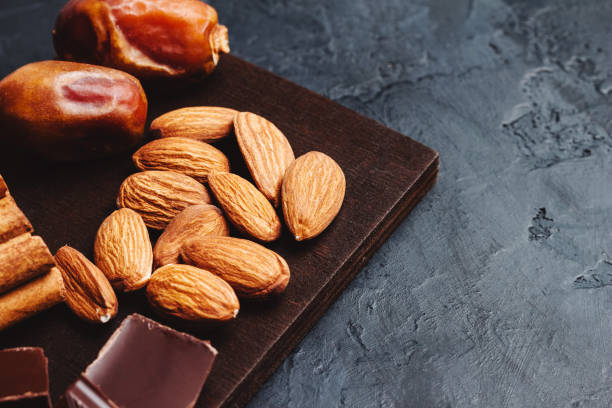 istock Chocolate cubes, nuts, dates and cinnamon sticks, healthy eating on a dark background 1127304646
