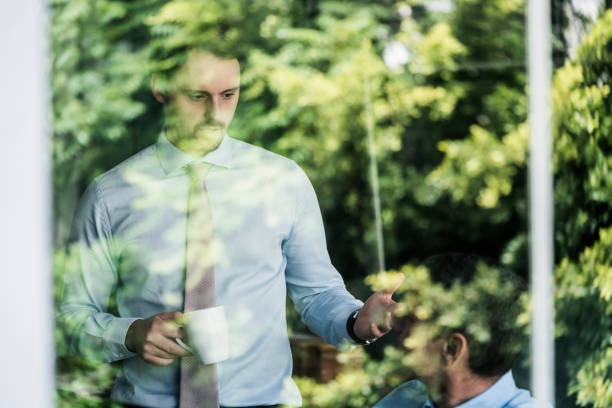 istock Businessman holding coffee cup talking to coworker 1127304927