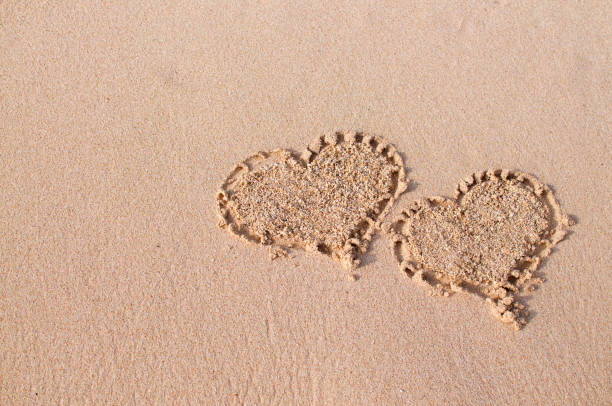 istock Two heart shapes in the sand 1127305172
