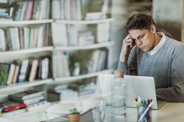 ホーム オフィスでラップトップで問題のある電子メールを読んで半ば大人のビジネスマン。 - looking through window businessman problems reading ストックフォトと画像