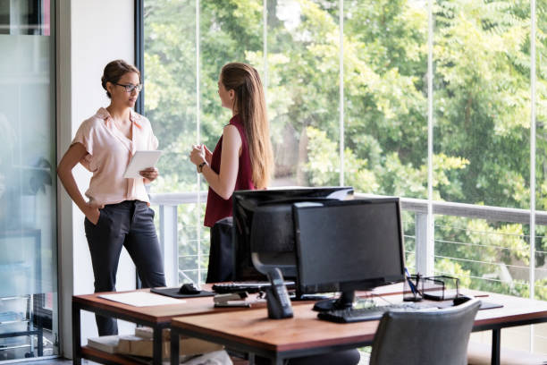 istock Businesswomen discussing while standing in office 1127305955