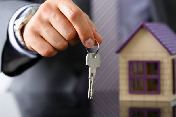 istock Man in suit and tie hold in hand silver key giving 1127306145