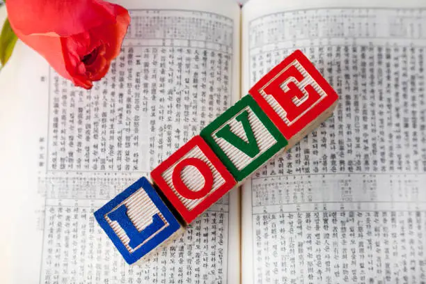 opened korean bible on the desk with love wooden cubic and red rose