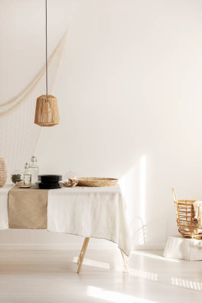 istock Rattan lamp above dining table with wicker pater and plates, copy space on empty white wall 1127306497