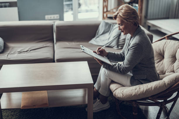 istock Serious woman making notes while sitting in the living room 1127307824