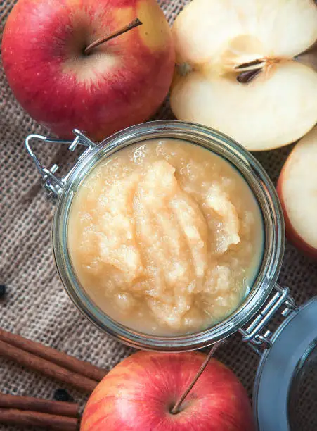 Fresh homemade applesauce with apples on a wooden table