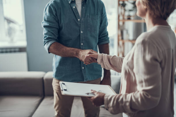 Close up of man shaking hands with his psychotherapist Man in casual clothes standing opposite his reliable psychotherapist and shaking her hand while coming to the meeting softness stock pictures, royalty-free photos & images