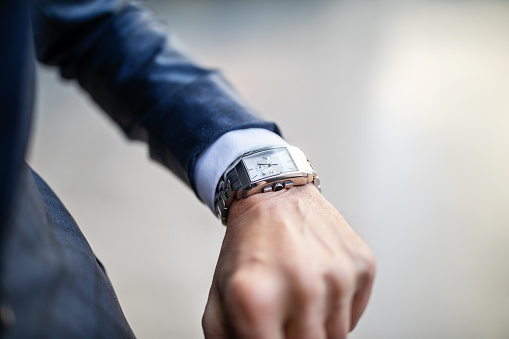 Close up of a man in formal clothes looking at watch. Man checking time on hie wristwatch.
