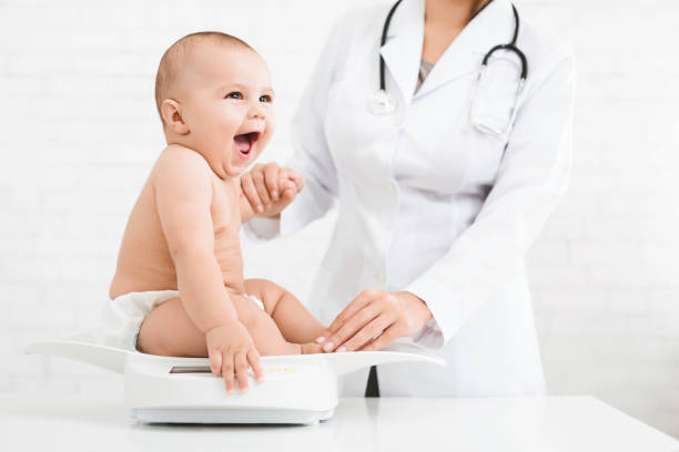 Adorable little baby child with female pediatrician Weight measuring. Adorable little baby sitting on scales , medical check up with female pediatrician, copy space pediatrician stock pictures, royalty-free photos & images