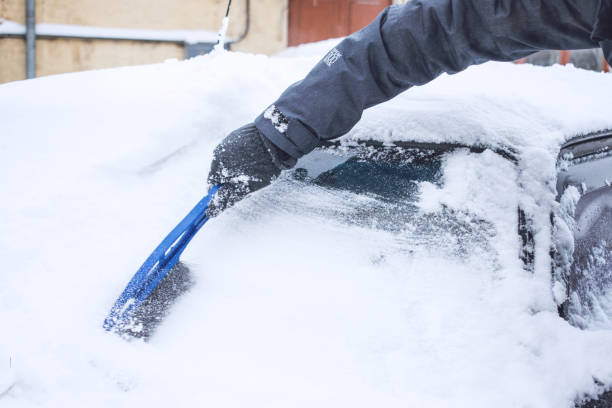 istock Man cleaning car from snow and ice with brush and scraper tool during snowfall. Winter emergency. Weather-related vehicle emergencies. Automobile covered with snow 1127312903