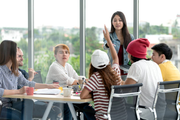 istock Young attractive asian creative hipster female leader standing at modern office happy talking and brainstorming idea presentation with teamwork. Casual asian people business meeting workshop concept. 1127312963
