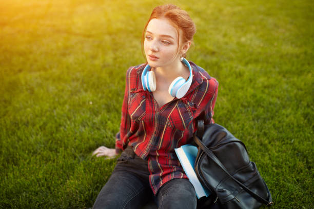 istock young beautiful student wearing a checkered shirt headphones and a backpack resting on the street between classes 1127313174