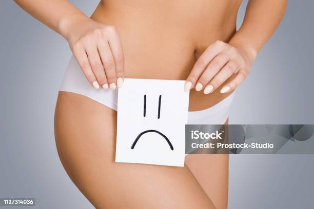 Woman Holding White Card With Sad Smile Near Hips Stock Photo - Download Image Now - Healthcare And Medicine, Reproductive Organ, Women