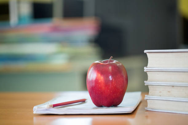 School teacher's desk with stack of books and apple, Educational concept.