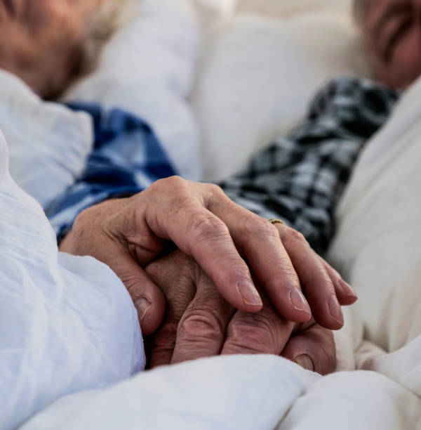 istock Elderly couple holding hands in bed 1127316223
