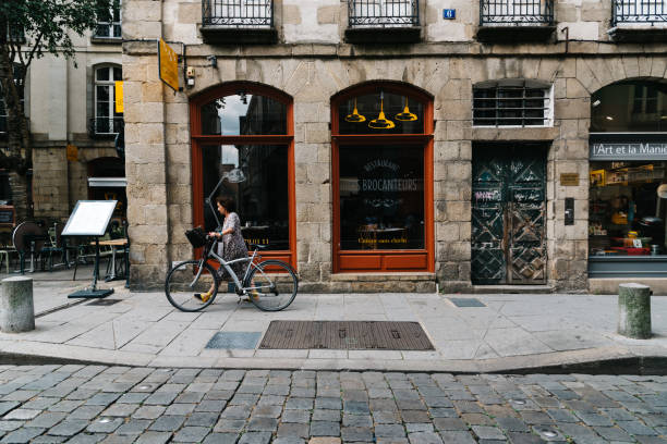 Woman with bicycle at restaurant showcase in Rennes Rennes, France - July 23, 2018: Woman with bicycle at restaurant showcase in historic centre of the city. rennes france photos stock pictures, royalty-free photos & images