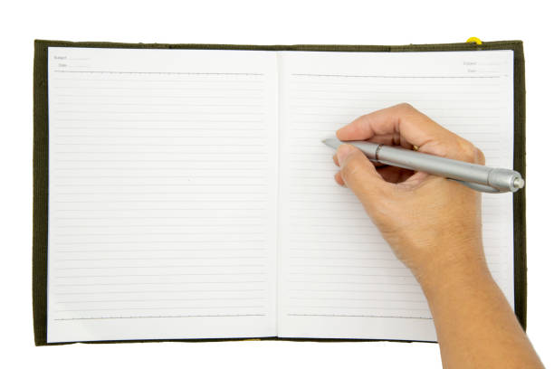 istock hand writing in a notebook with pencil on wood table. 1127317500