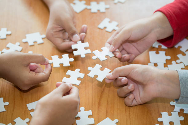 istock Hands of diverse people assembling jigsaw puzzle, team put pieces together searching for right match, help support in teamwork to find common solution concept, top close up view 1127317776