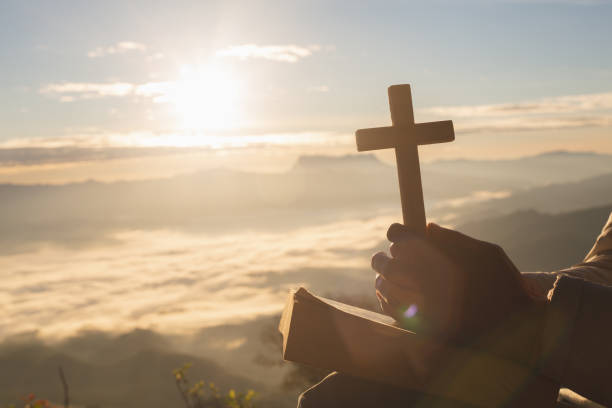 silueta de mano mujer santa elevación de la cruz cristiana con ligero fondo puesta de sol - praying human hand worshipper wood fotografías e imágenes de stock