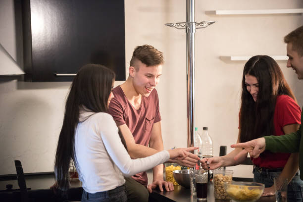 istock Four young friends standing on kitchen spending time together. Spiling drinks 1127320271