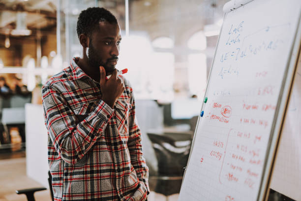 istock Young man thoughtfully touching his chin and looking at flipchart 1127320906