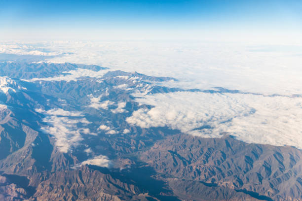 Wing of an airplane flying above the clouds with blue sky. View at the sky from the window of the plane.