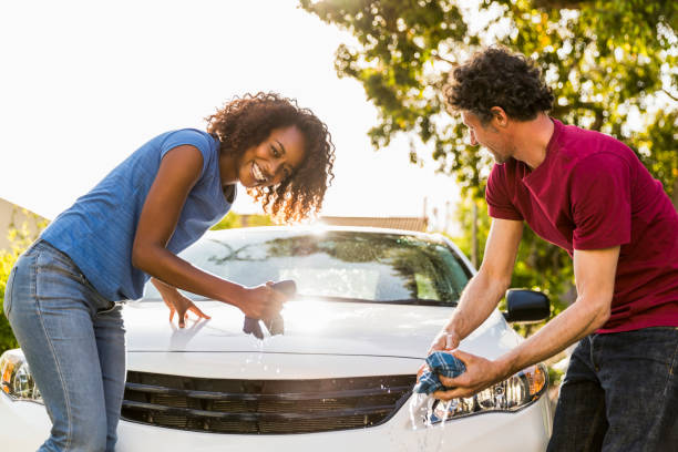 istock Cheerful woman cleaning car with man at yard 1127323045
