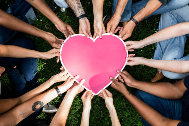 istock Group of people holding a pink heart icon 1127330114