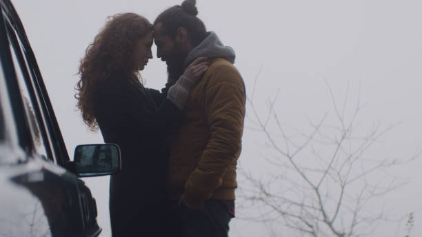 istock Cheerful young couple on road trip. Hugging next to a car 1127330513