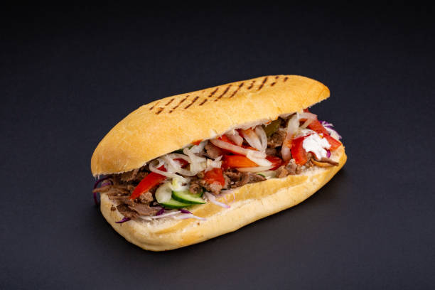 istock Ciabatta bread stuffed with cheese,meat and vegetables on dark background,selective focus and blank space 1127330968