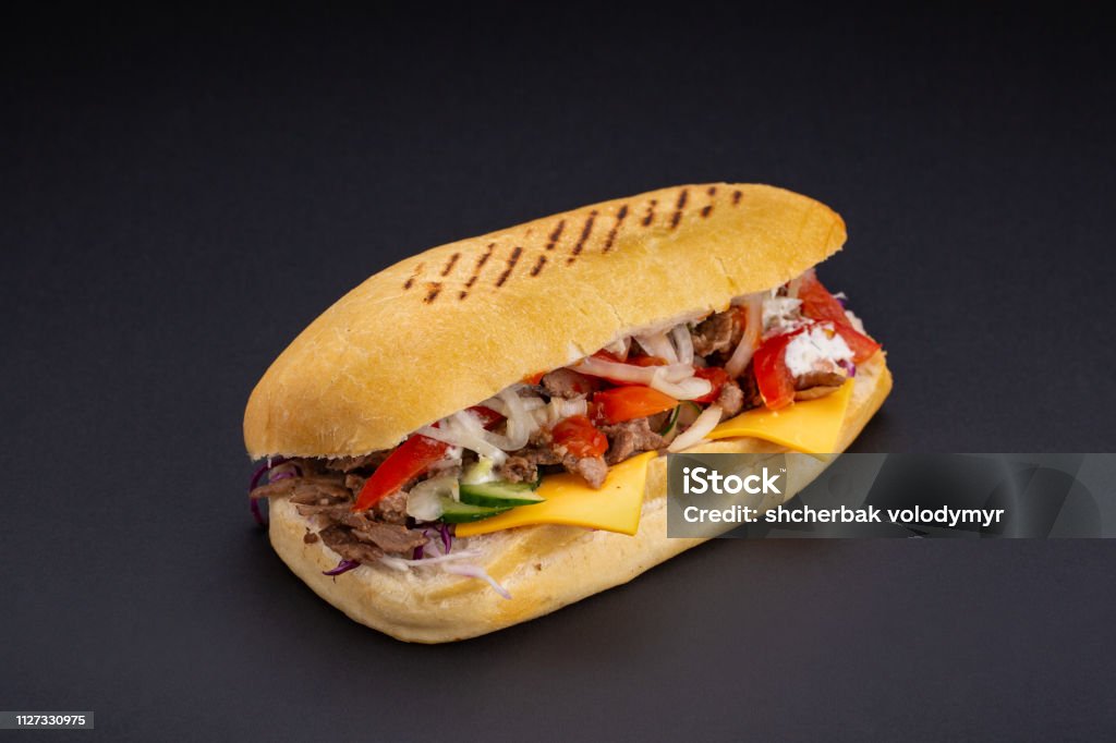 Ciabatta-Brot gefüllt mit Käse, Fleisch und Gemüse auf dunklem Hintergrund, Tiefenschärfe und Leerzeichen - Lizenzfrei Brotsorte Stock-Foto