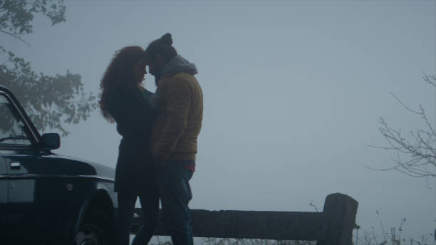istock Cheerful young couple on road trip. Hugging next to a car 1127332605