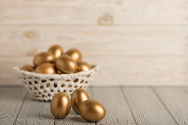 istock Happy easter! Easter eggs of golden color on a light wooden background. 1127336724